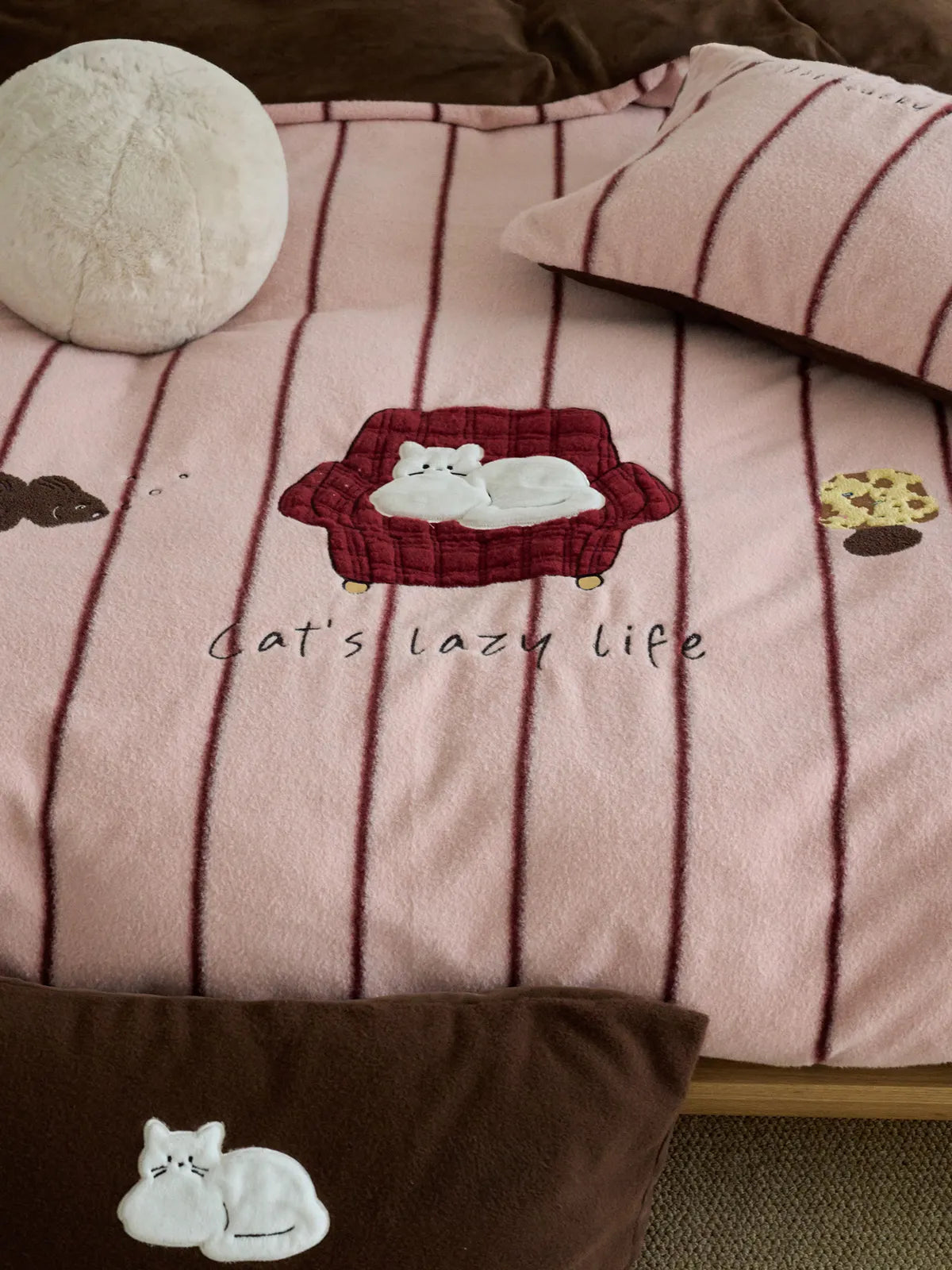 Pink Cartoon Striped Flannel Fleece Bedding Set with 'Lazy Cat' embroidery, shown styled on a bed with matching pillows. - RoomDen