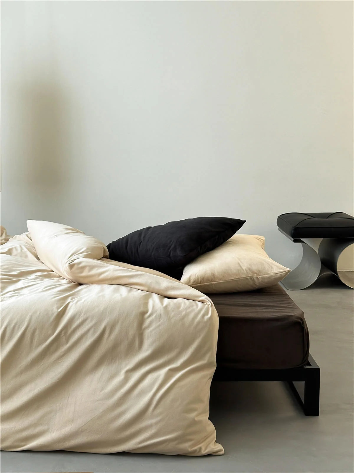 Side angle of a bed with a Warm Beige velvet duvet cover on a Mocha Brown sheet in a bright, airy room. - RoomDen