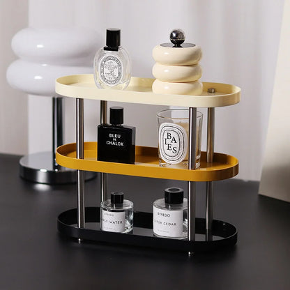 The three-tier tricolor makeup organizer holding perfume bottles and a candle on a desk. - RoomDen