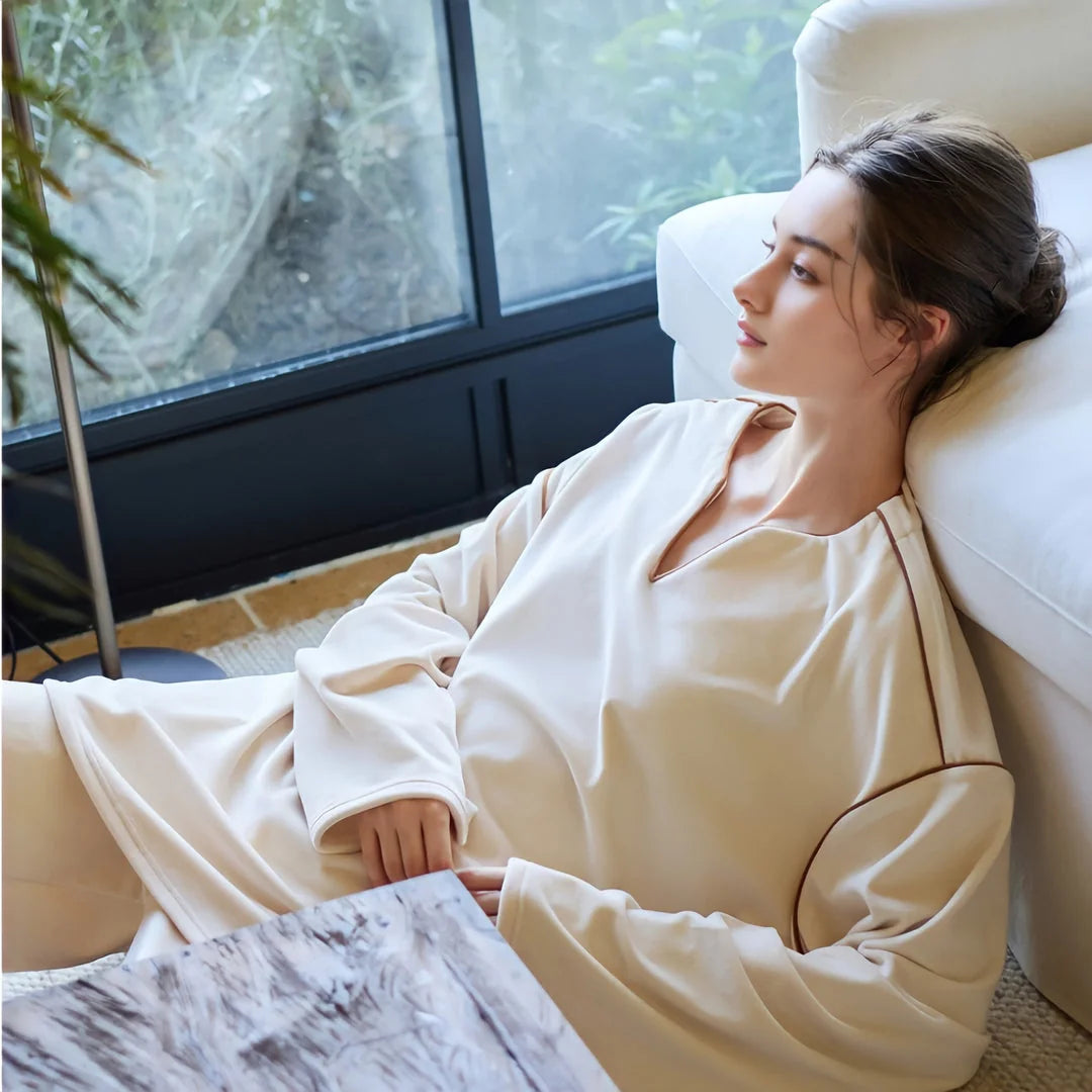 Model lounging on the floor in the plush pajama set, looking out a large window. - RoomDen