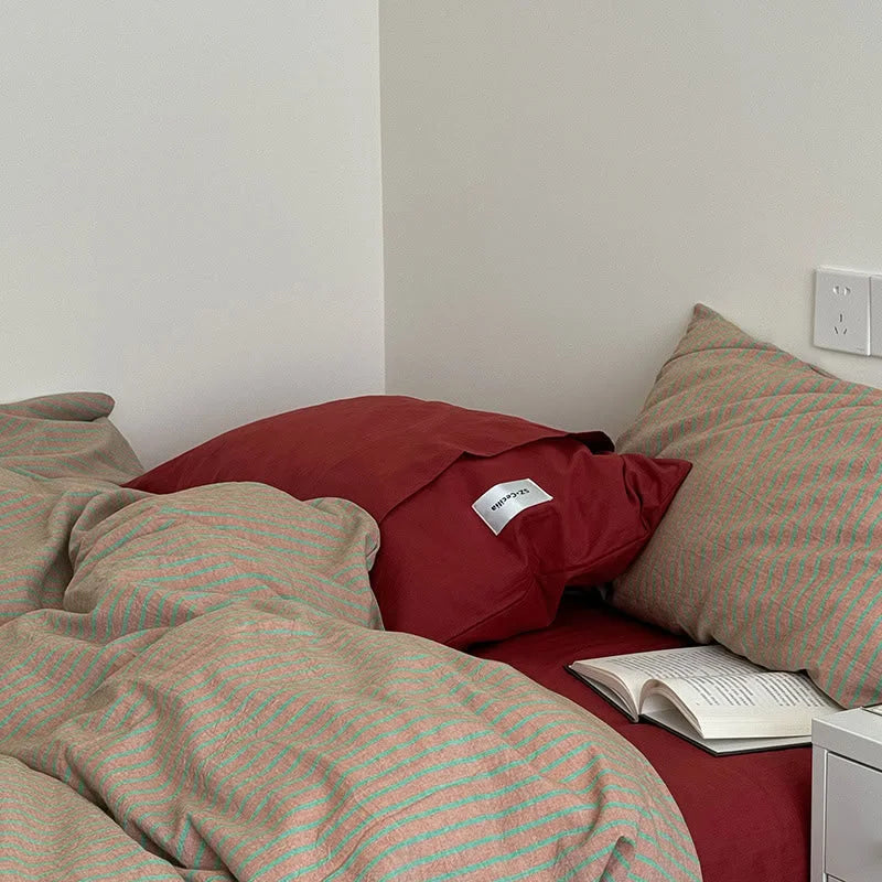 Detailed shot of the corner of the bed, showing the texture of the Red & Green Striped duvet and a solid red pillowcase - RoomDen.