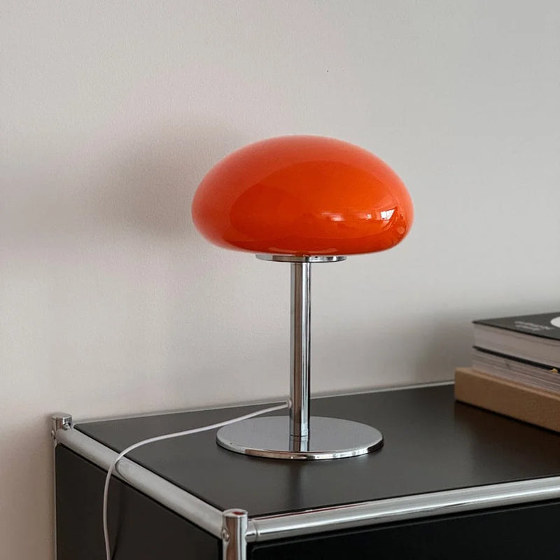 The orange mushroom lamp with its chrome metal base on a black surface — RoomDen