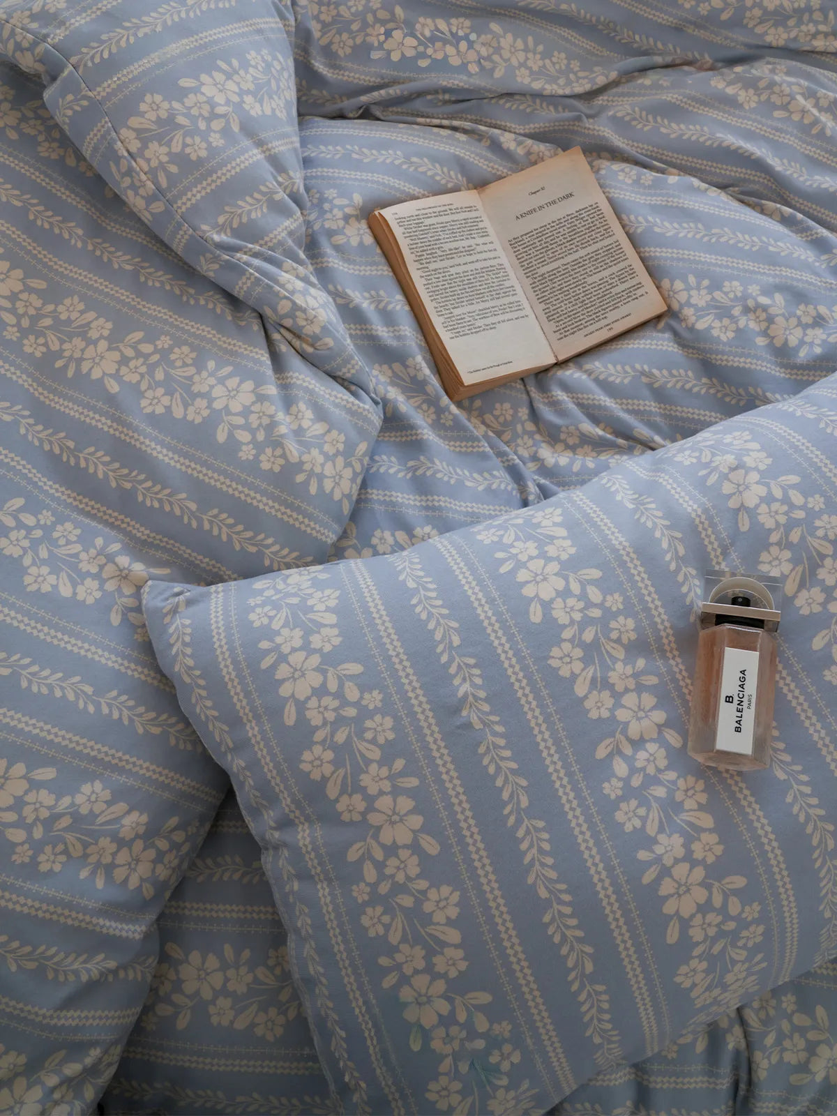 Overhead shot of the vintage-style floral stripe bedding, with an open book resting on the plush duvet. - RoomDen