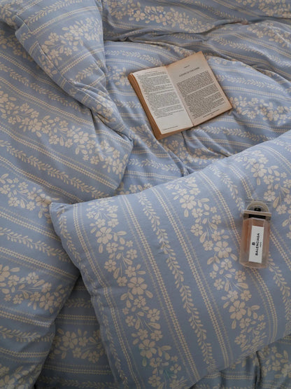 Overhead shot of the vintage-style floral stripe bedding, with an open book resting on the plush duvet. - RoomDen