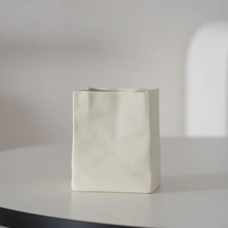 A single cream white crumpled ceramic organizer on a white table with soft lighting. - RoomDen