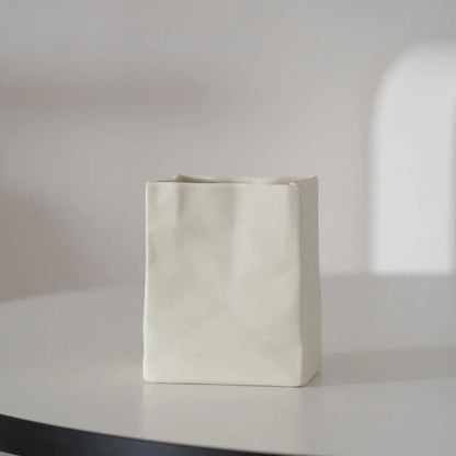 A single cream white crumpled ceramic organizer on a white table with soft lighting. - RoomDen