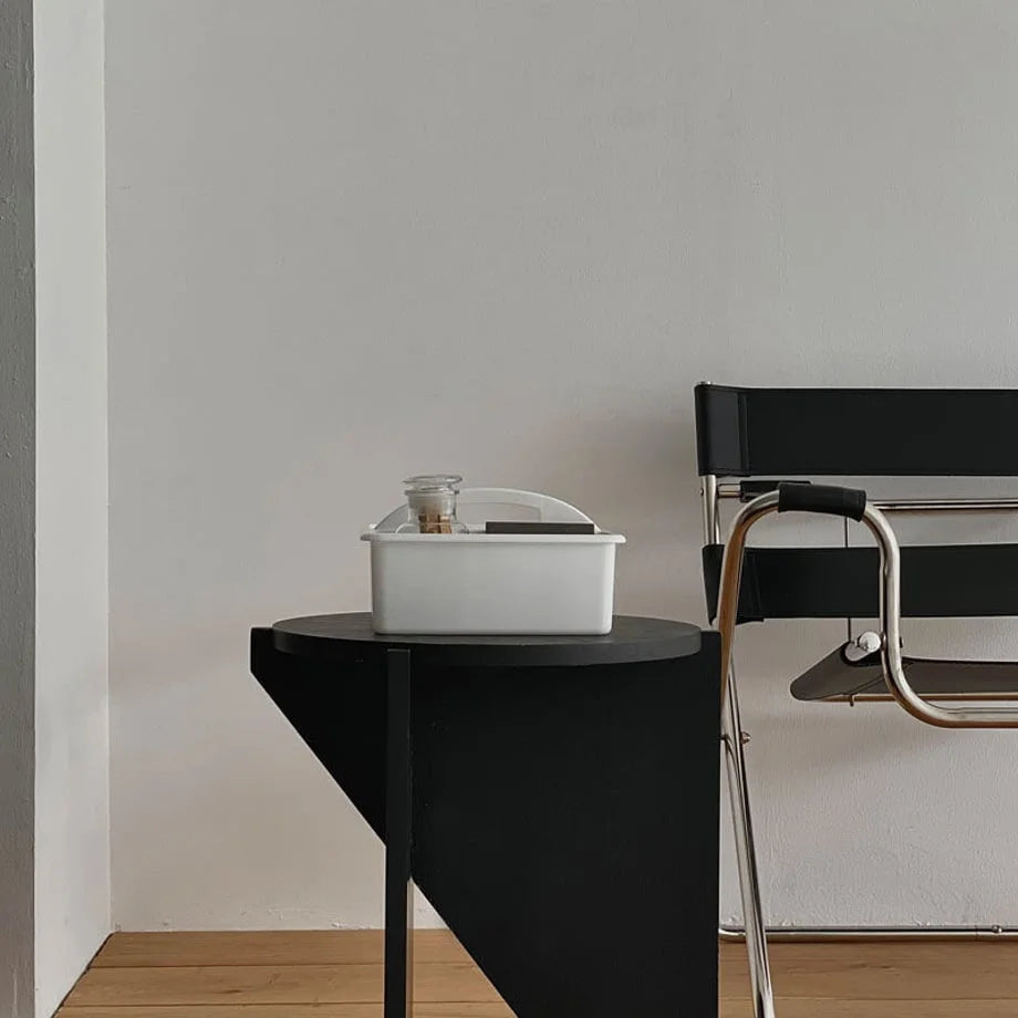 White portable organizer caddy on a black side table next to a modern black leather chair. - RoomDen