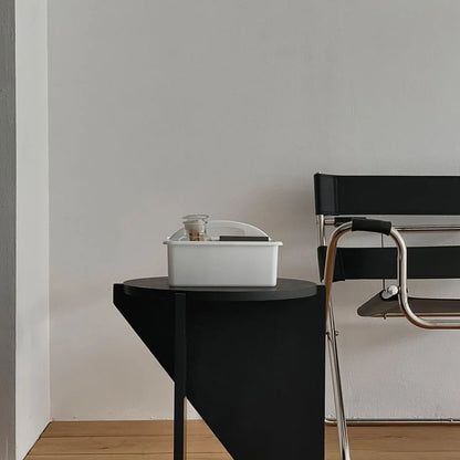 White portable organizer caddy on a black side table next to a modern black leather chair. - RoomDen