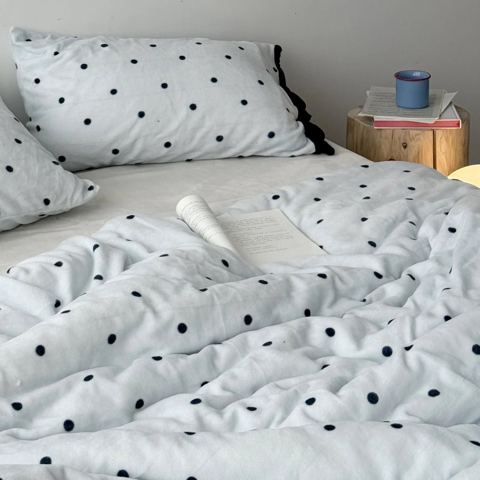 Close-up of the cozy Light Blue Polka Dot Flannel Fleece Duvet Cover with a book resting on it.