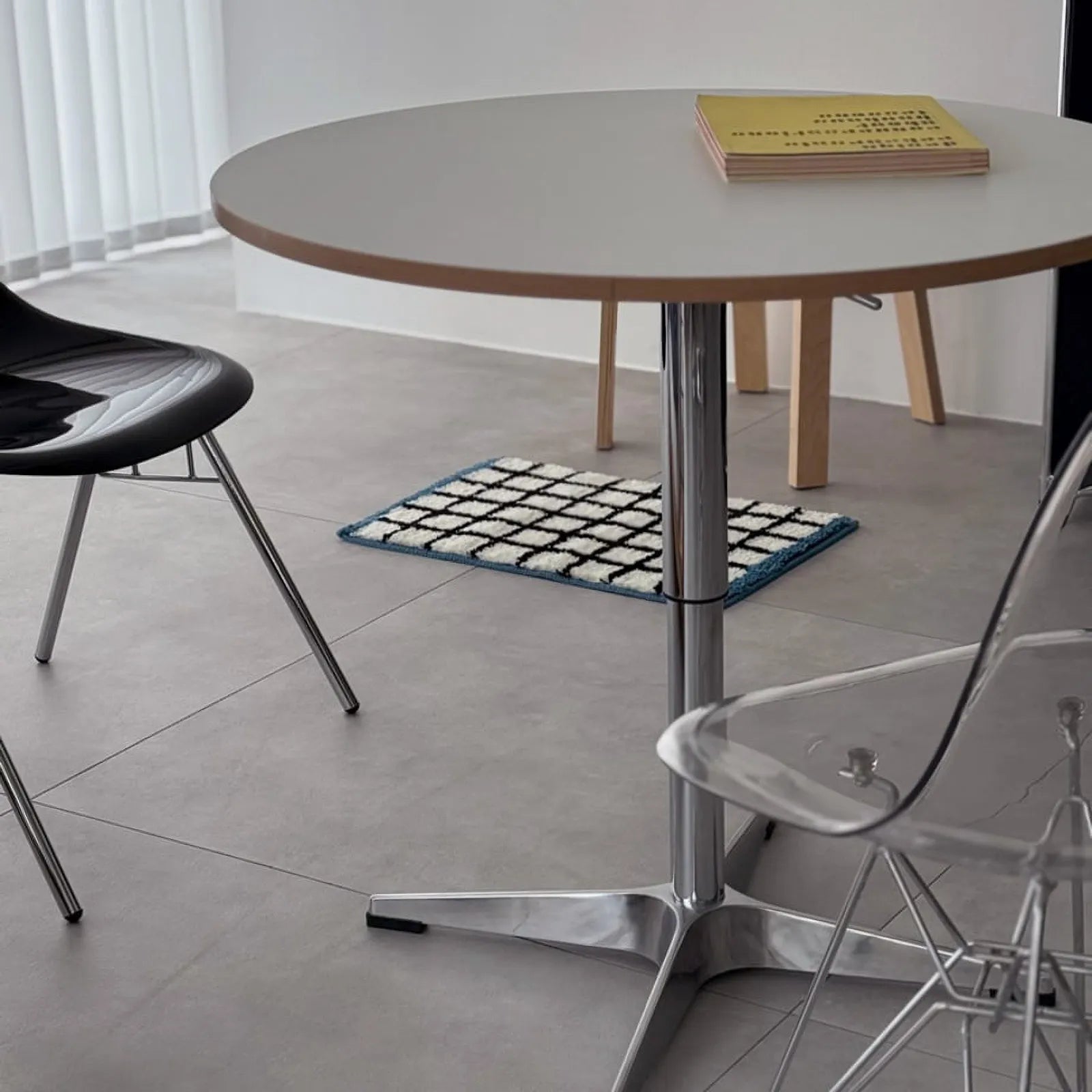Lifestyle scene showing the grid rug placed under a round table with modern chairs - RoomDen