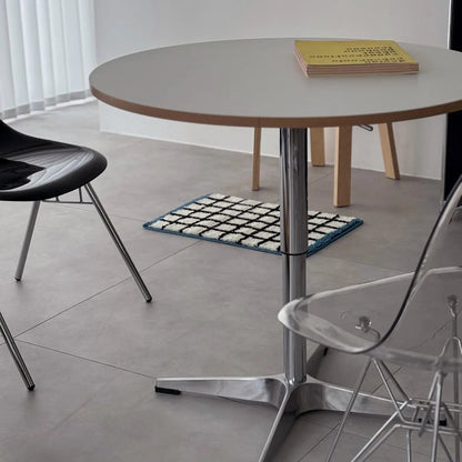 Lifestyle scene showing the grid rug placed under a round table with modern chairs - RoomDen