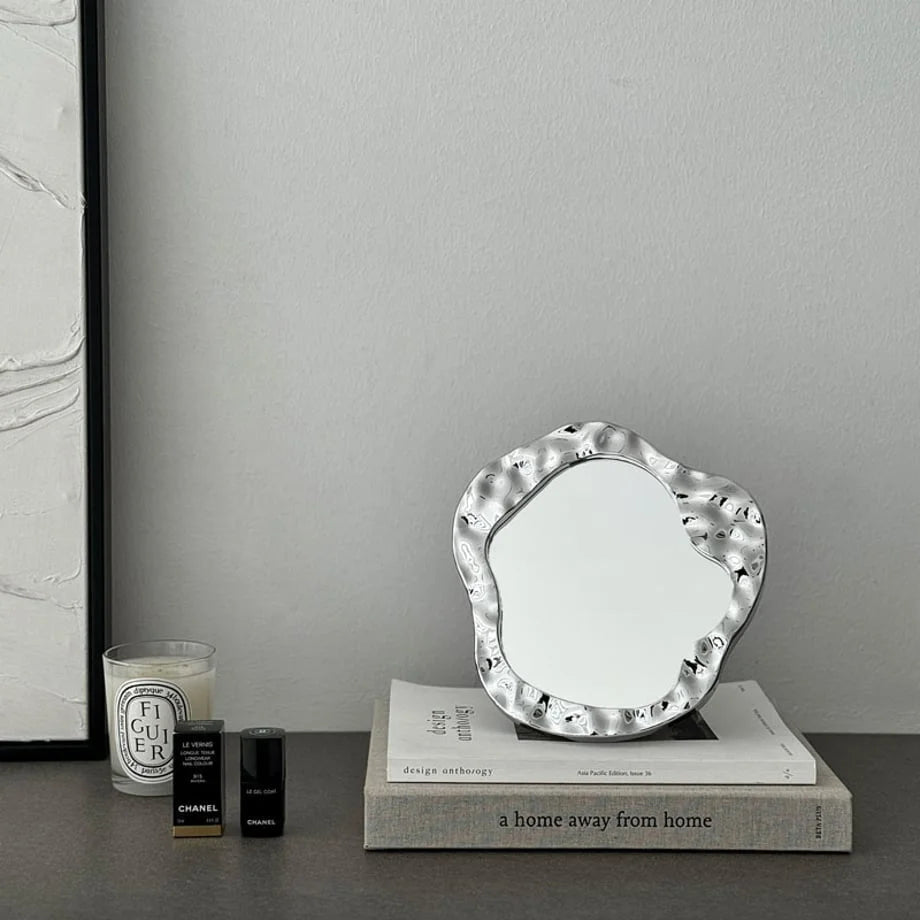 Wide view of the wavy chrome vanity mirror adding a Y2K touch to a minimalist grey desk - RoomDen
