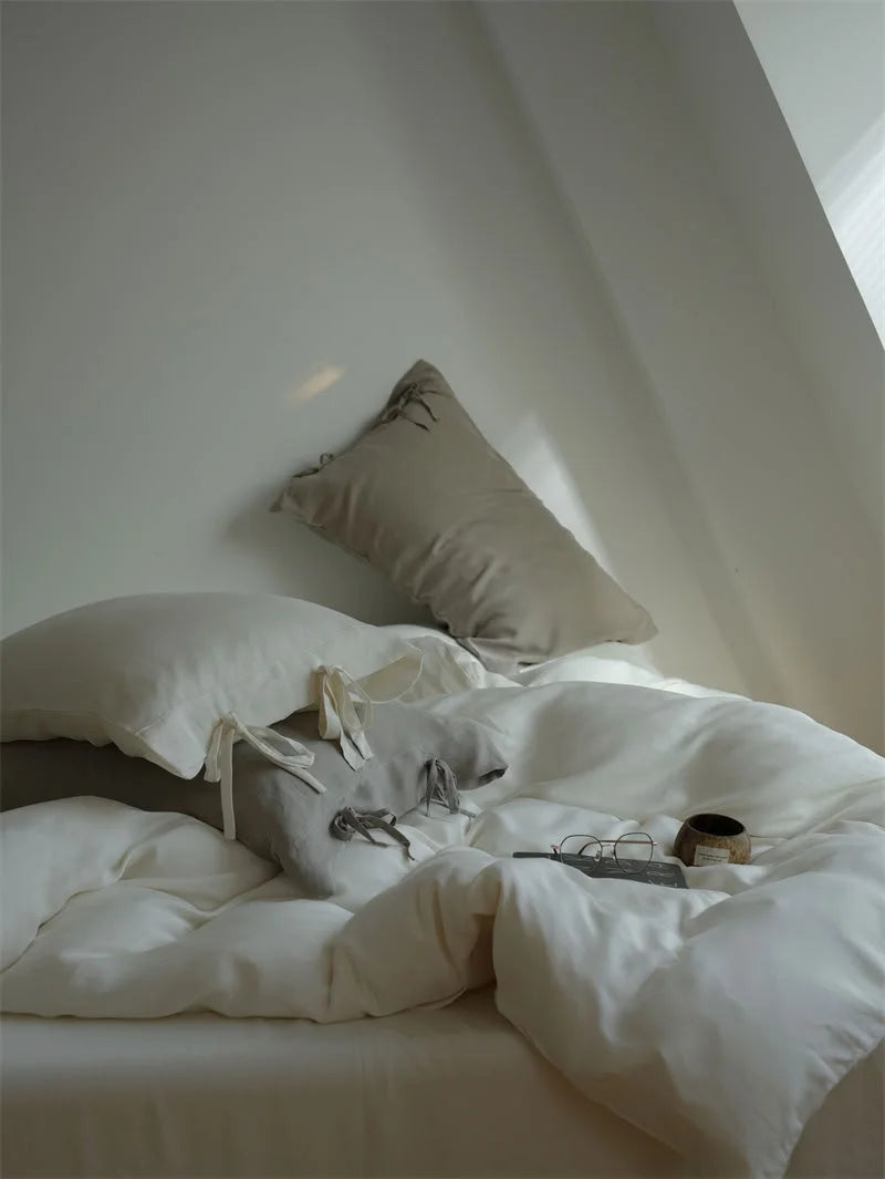 View of the tie-closure pillowcases in Creamy White and Misty Grey on a neatly made bed - RoomDen