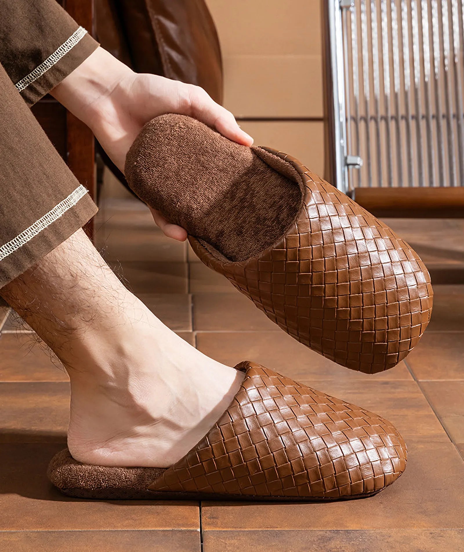 Model wearing brown woven slippers sitting on a tiled floor - RoomDen
