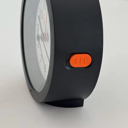 Close-up of the orange alarm switch on the side of the black Minimalist Matte Analog Alarm Clock. - RoomDen