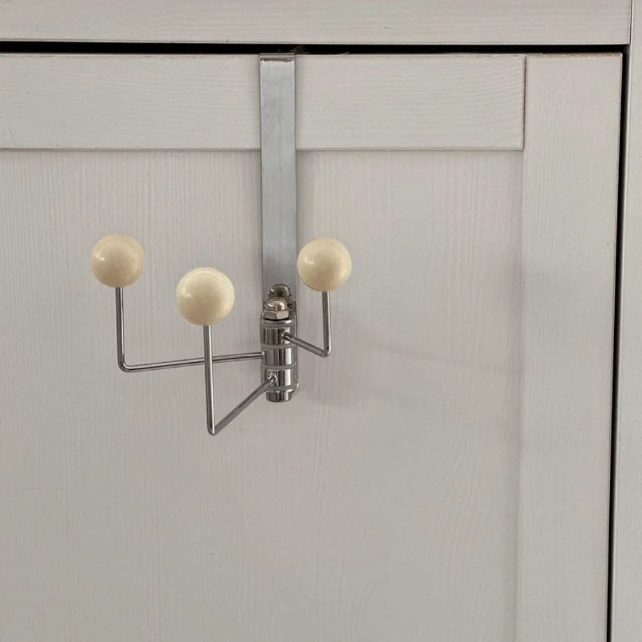 The beige over-the-door hook shown on a white cabinet door, demonstrating its versatile use - RoomDen