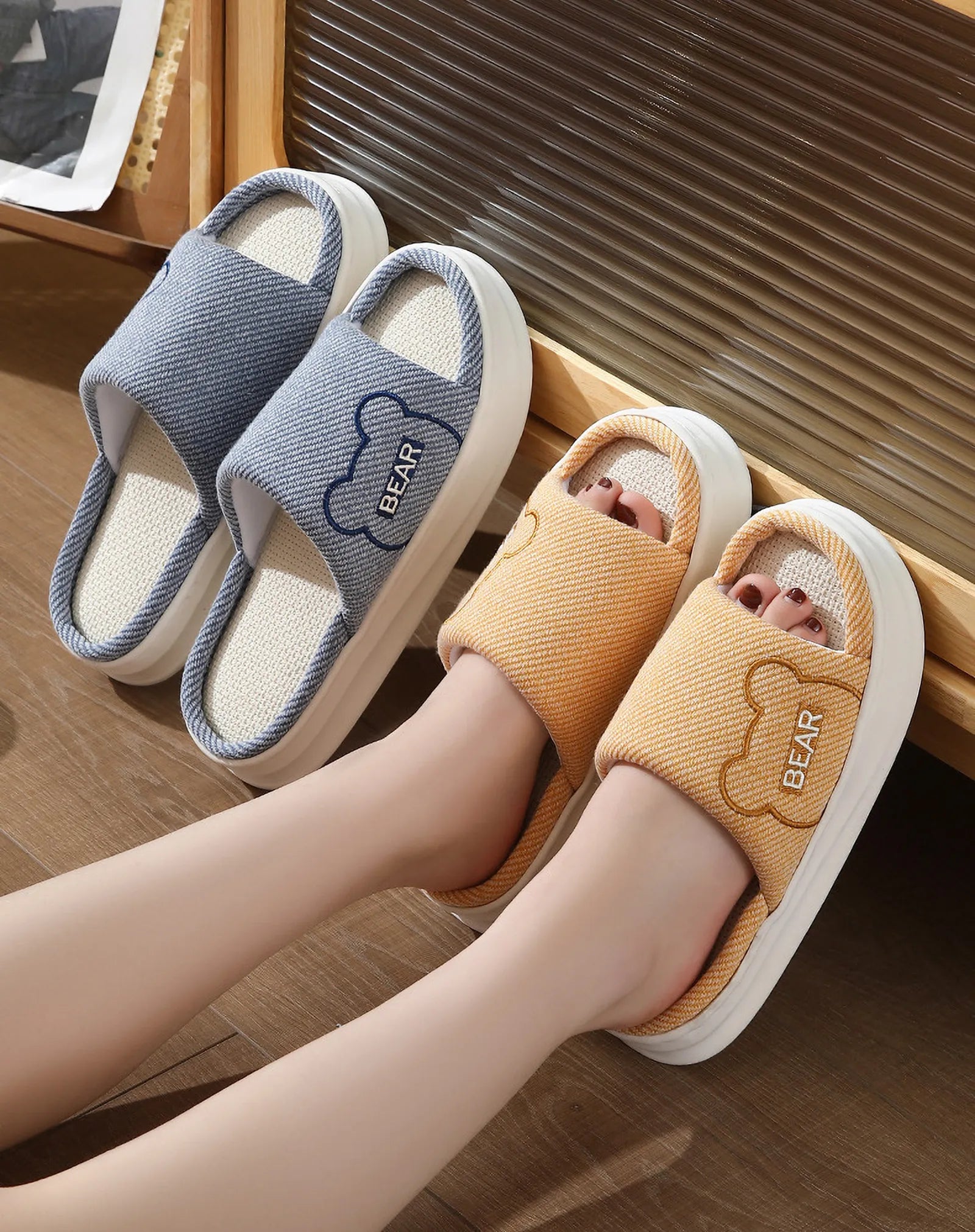 Blue and Orange textured linen house slippers with bear embroidery leaning against wall