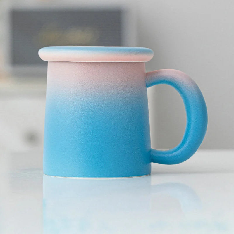 Side view of the Pink & Blue Ombre Frosted Ceramic Mug with lid on a white surface - RoomDen.