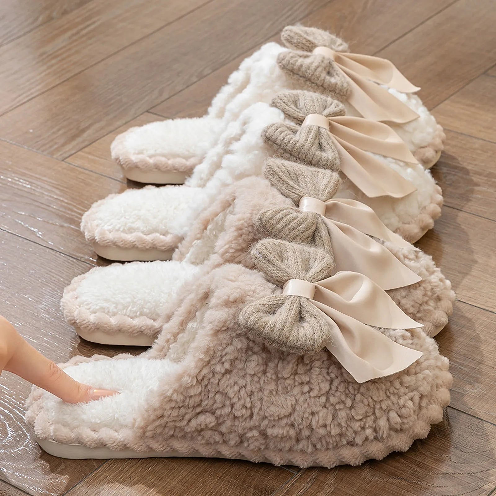 Side view of four color variants of fuzzy bow slippers lined up on wood floor - RoomDen