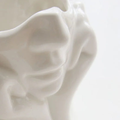 Detailed close-up of the sculpted facial features on the white resin vase - RoomDen.