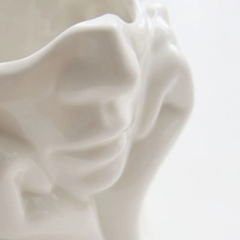 Detailed close-up of the sculpted facial features on the white resin vase - RoomDen.