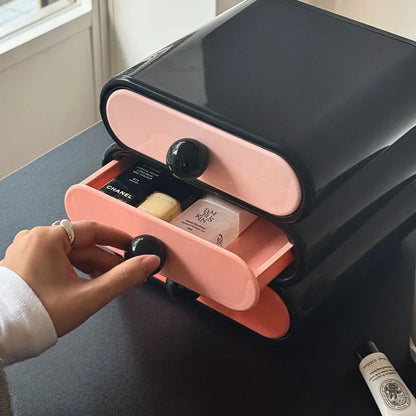 Hand opening the middle pink drawer of the wavy makeup organizer, showing stored cosmetics. - RoomDen