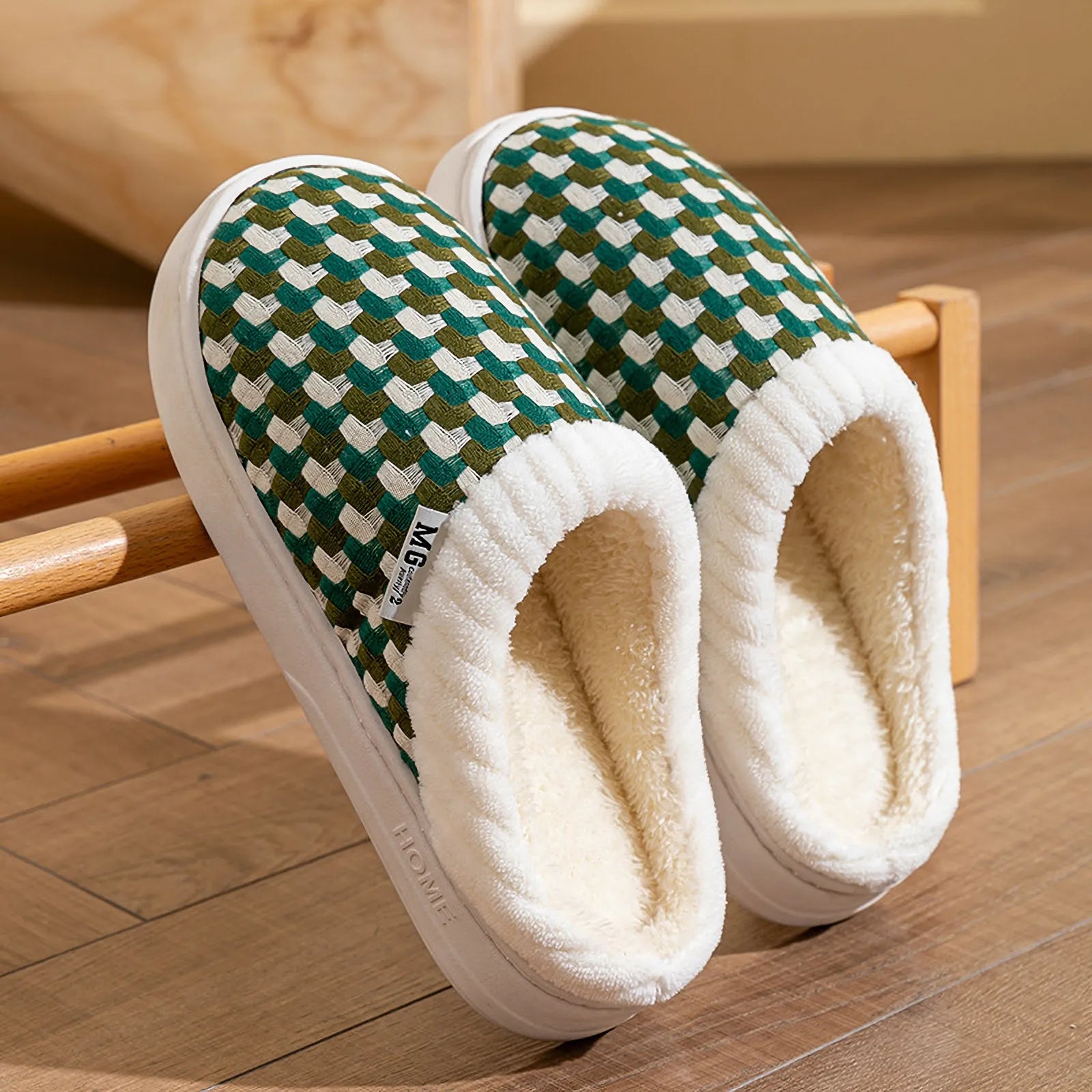 Pair of green and white woven plush slippers resting on wooden rack