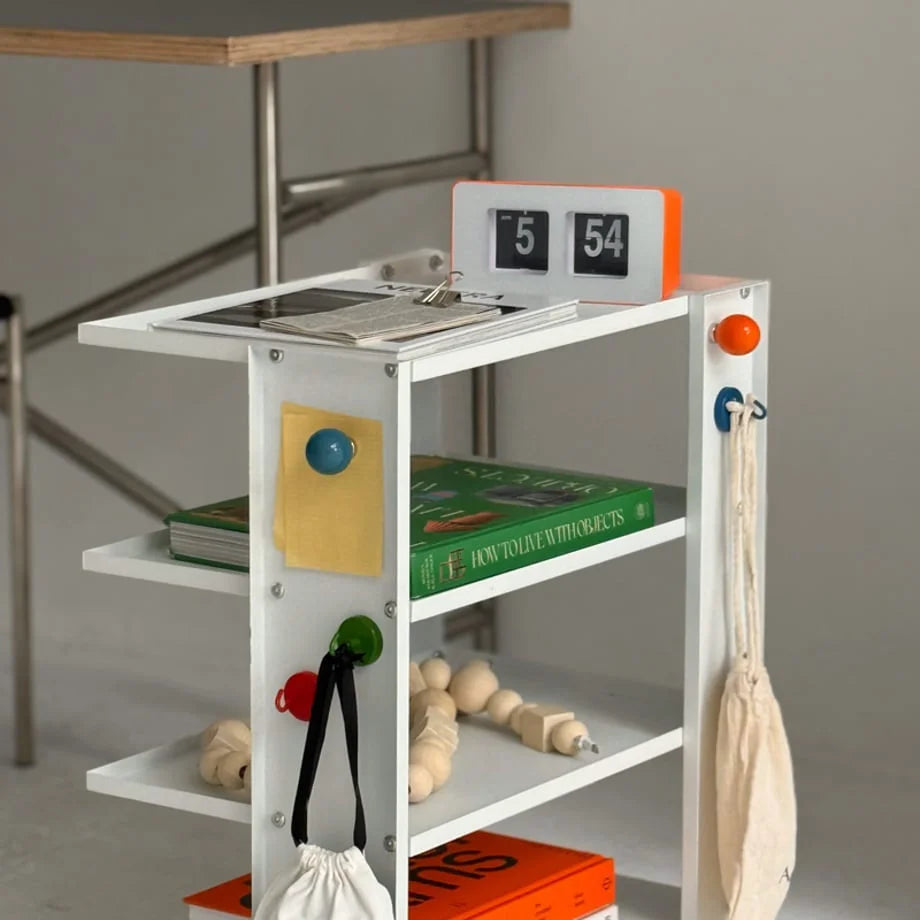 Colorful magnetic hooks on a white shelving unit holding small bags and notes in a bright room - RoomDen