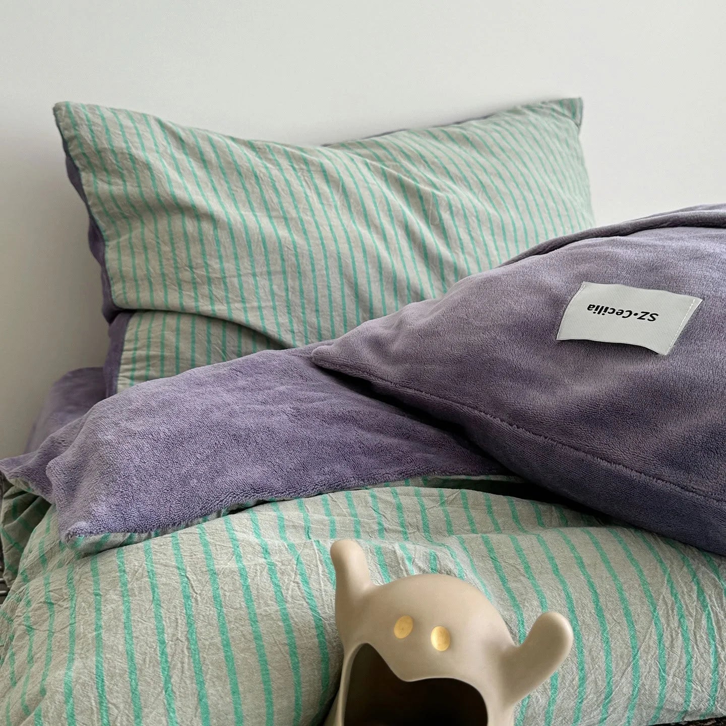 Detail of the purple fleece and mint striped pillowcases from the reversible bedding set.