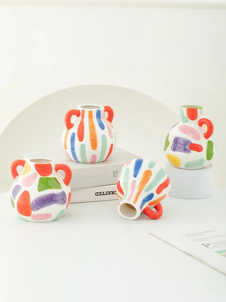 A collection of four hand-painted colorful abstract ceramic vases, showing all styles and shapes on a white surface. - RoomDen