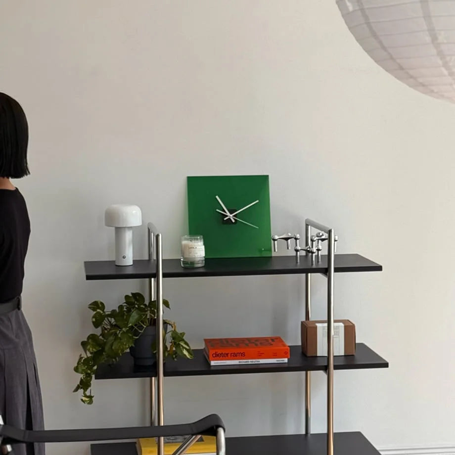 Emerald Green acrylic clock displayed on a minimalist black shelf with a candle and plant. - RoomDen