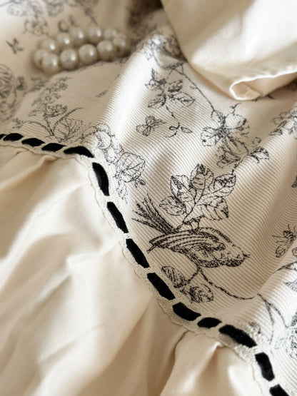 Detailed close-up of the botanical toile fabric and black stitched trim on the Cream Toile bedding. - RoomDen