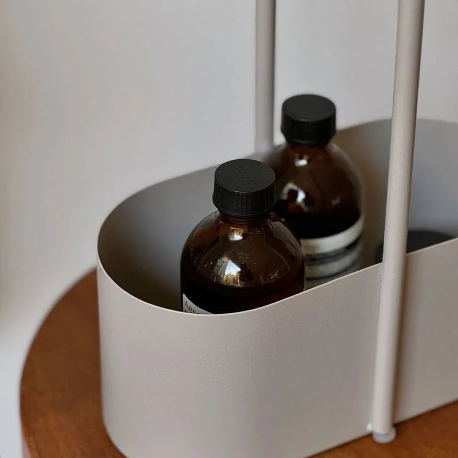 Detailed shot of the matte metal finish of the beige organizer, with amber bottles inside. - RoomDen