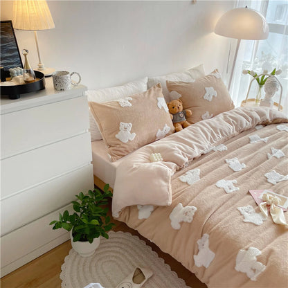 The creamy beige teddy bear bedding set styled on a bed with a teddy bear plush toy and a plant nearby. - RoomDen