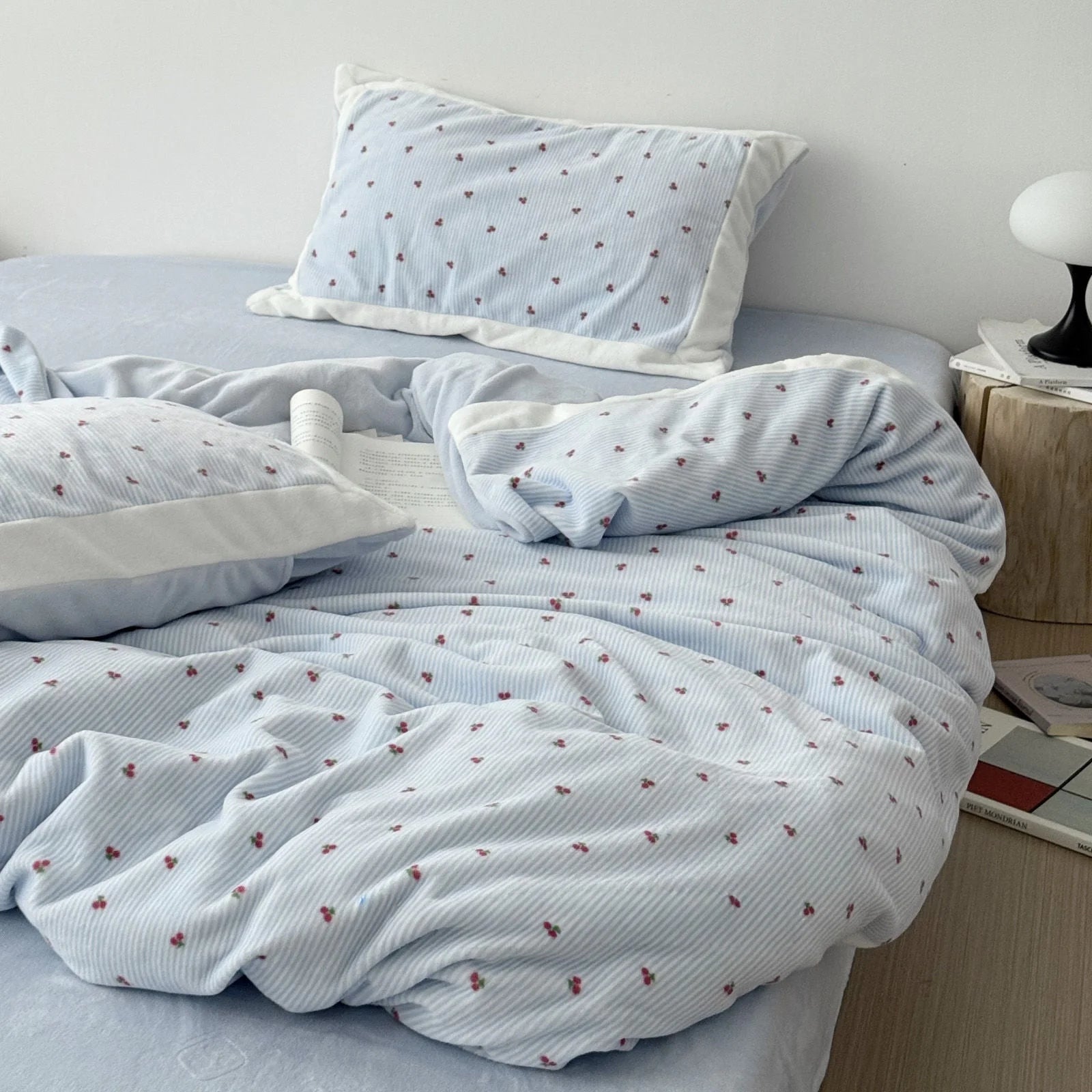 Full view of a bed made with a light blue cherry pinstripe flannel fleece duvet cover set in a bright, minimalist room - RoomDen.