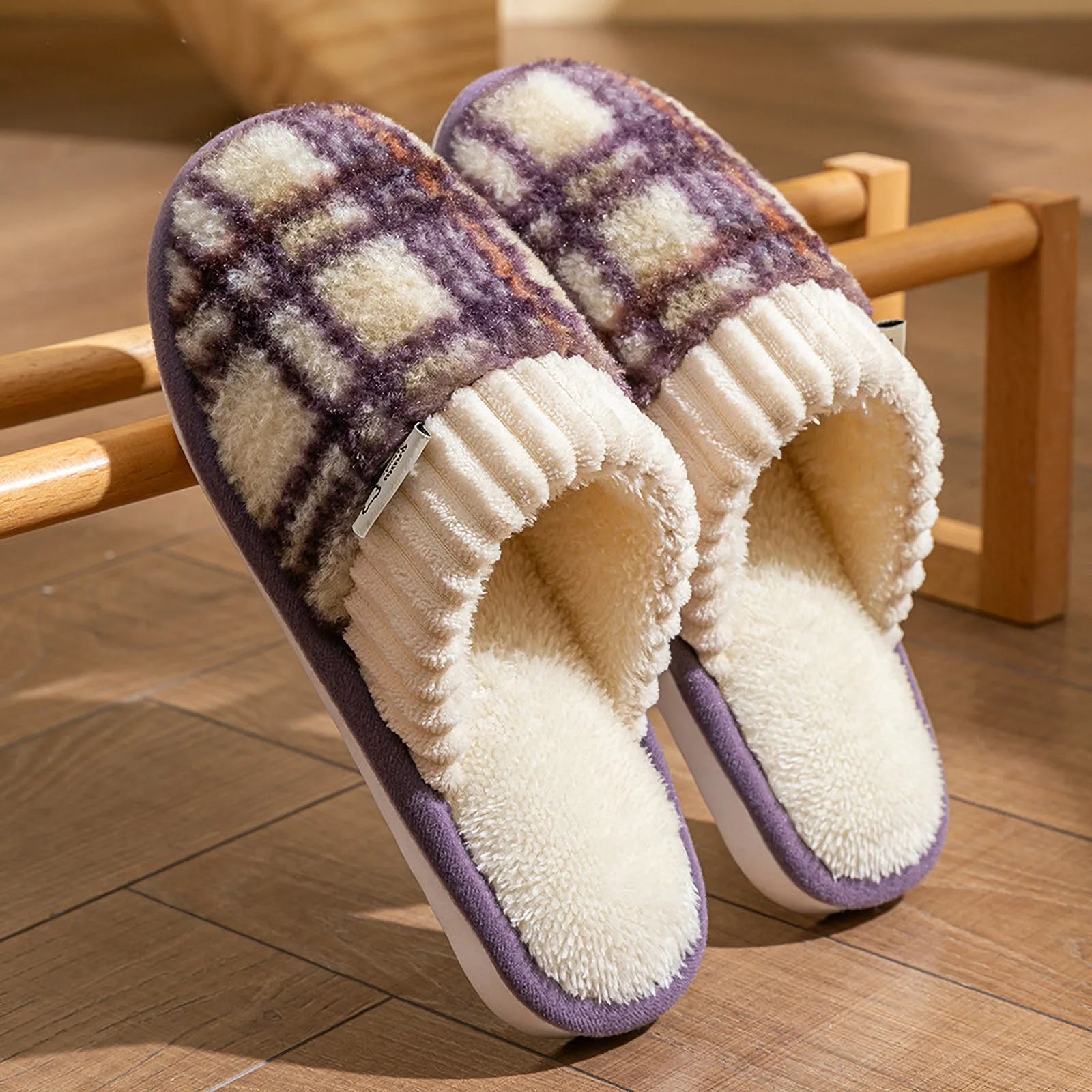 Purple and cream plaid sherpa slippers leaning against a wooden rack showing texture - RoomDen