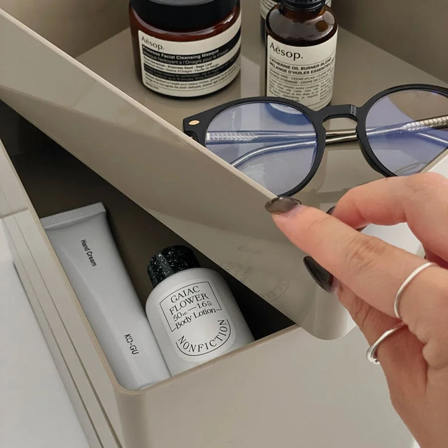 A hand opening a tier of the Khaki Grey rotating organizer to show lotions inside. - RoomDen