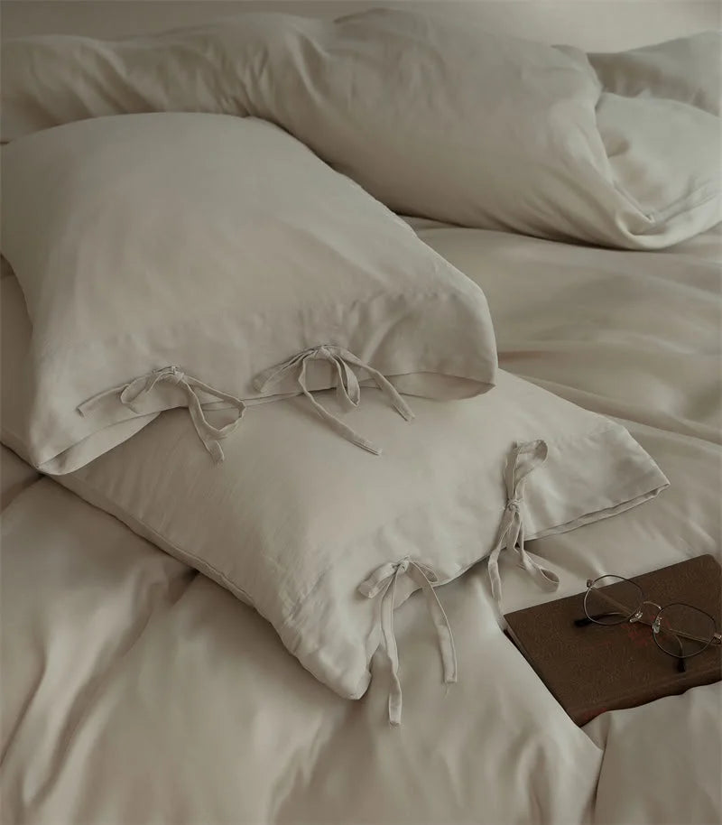 Detailed view of two Oatmeal Beige Tencel pillowcases with their delicate tie closures - RoomDen