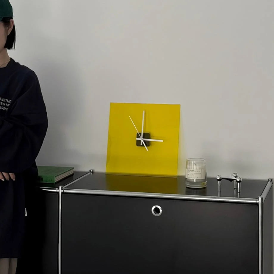 Zesty Yellow acrylic clock on a black cabinet with a person in a green cap standing nearby. - RoomDen