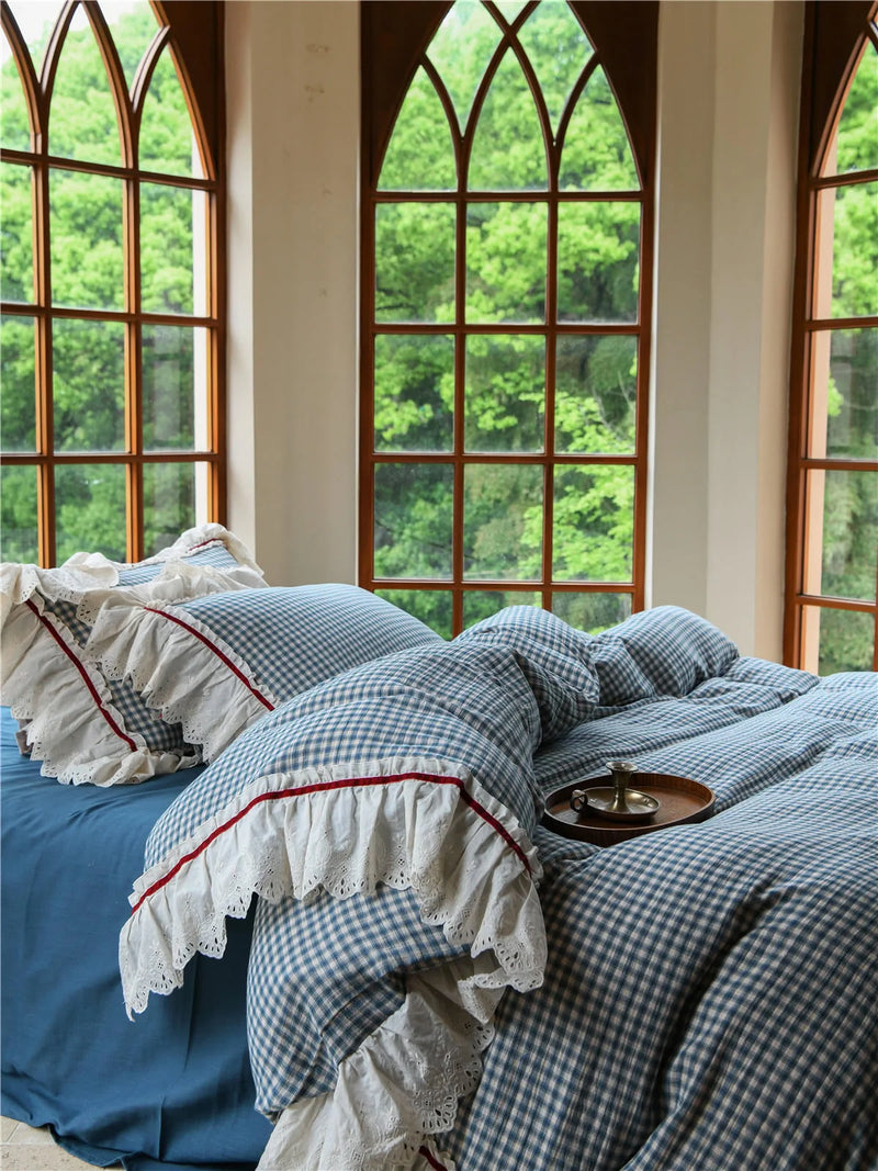 Close-up of the pillow shams showing embroidered lace ruffle trim on the gingham cottagecore bedding. — RoomDen