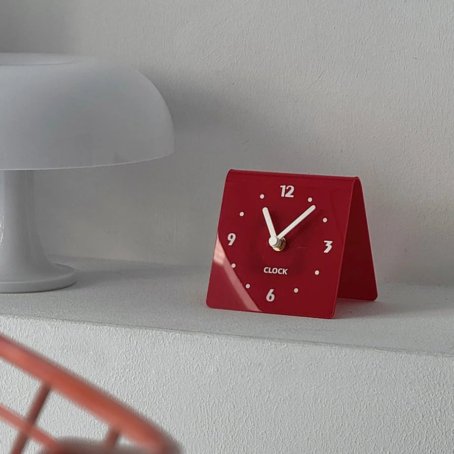 Close-up of the red Sleek Minimalist Metal Table Clock on a white shelf. - RoomDen