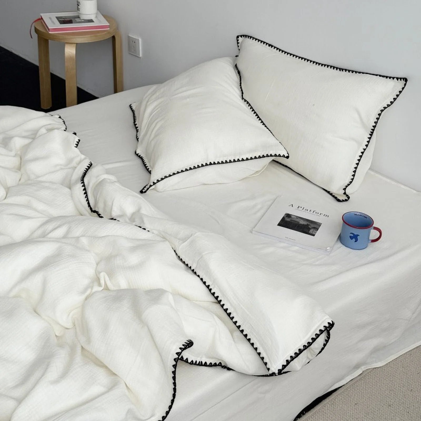 Full bed view of the cream white washed cotton set with black trim in a minimalist room.