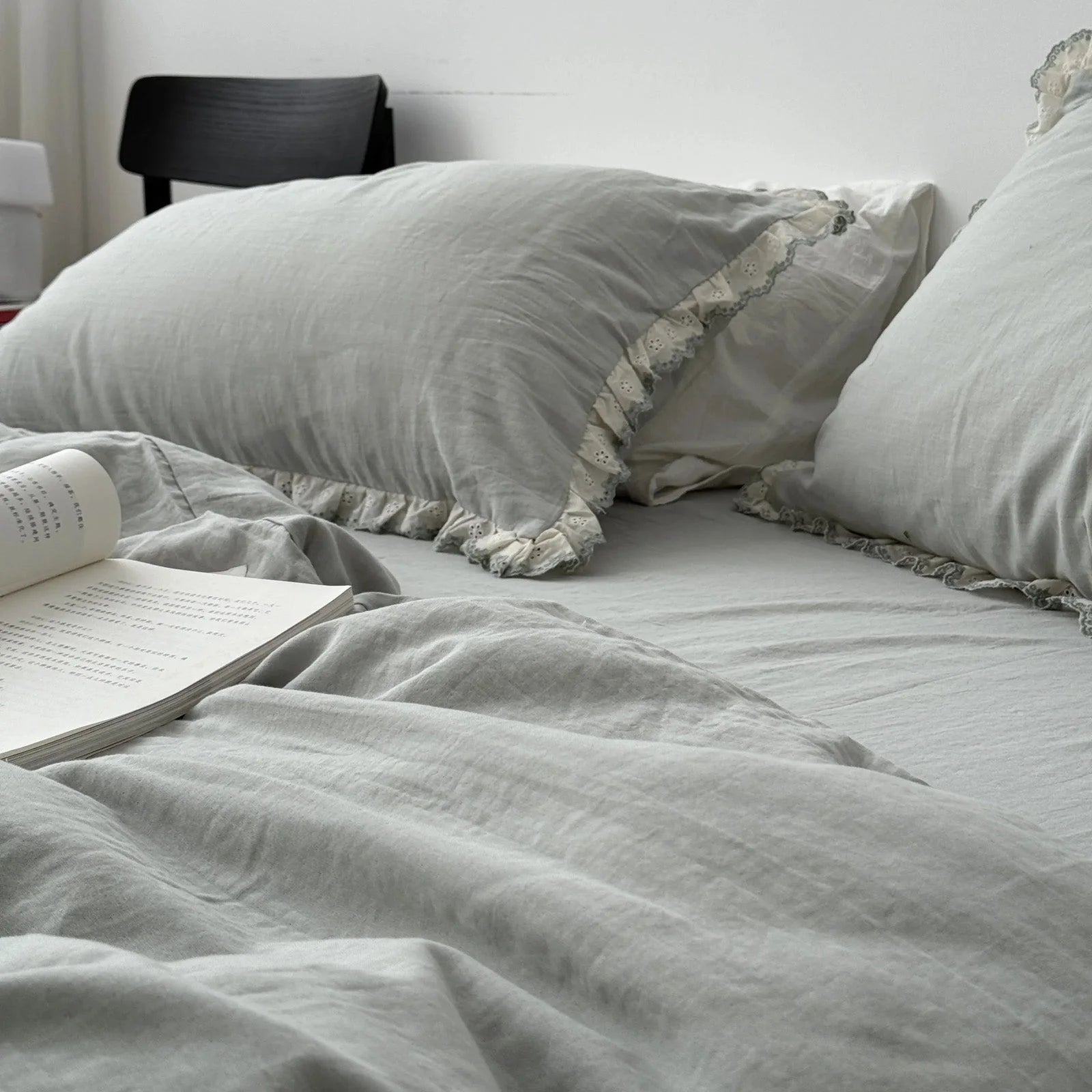 Side view of the sage green bedding set with a book, showing the gentle drape of the washed cotton duvet cover.