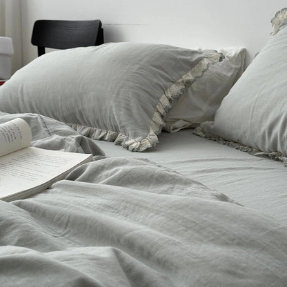 Side view of the sage green bedding set with a book, showing the gentle drape of the washed cotton duvet cover.