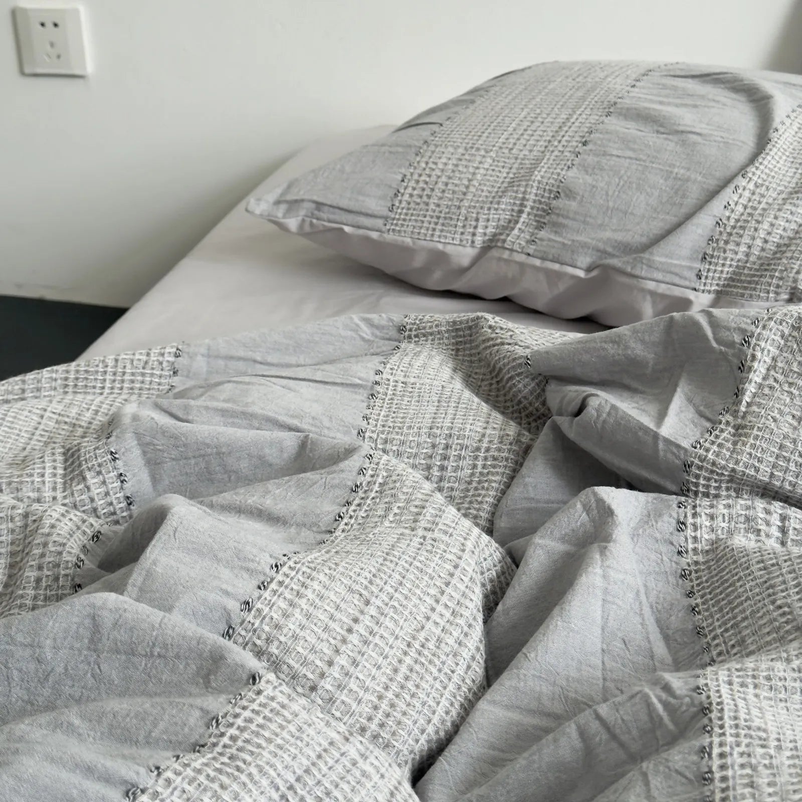 Detailed shot of the rumpled texture and woven stripes on the Cloud Grey duvet cover.