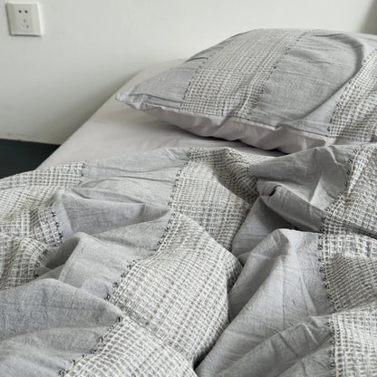 Detailed shot of the rumpled texture and woven stripes on the Cloud Grey duvet cover.