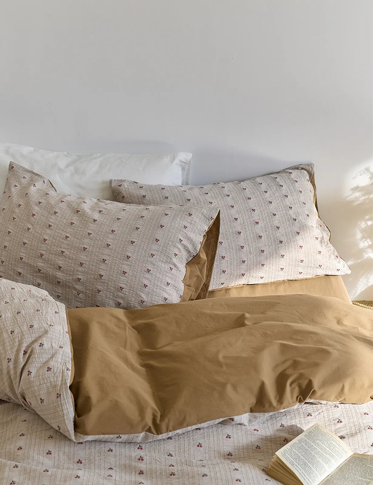 The Ditsy Cherry Washed Cotton Bedding Set on a bed, showing the reversible mocha brown side folded over - RoomDen.