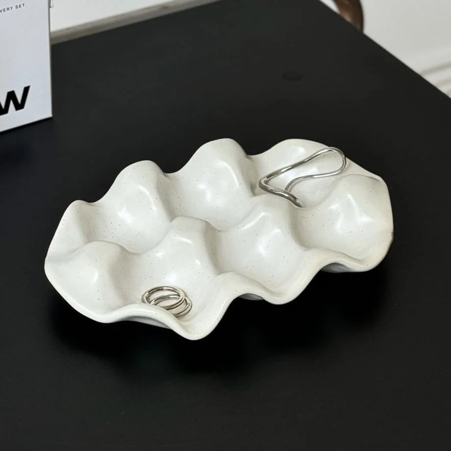 Top-down view of the Speckled Wavy Ceramic Jewelry Dish with two silver rings.
