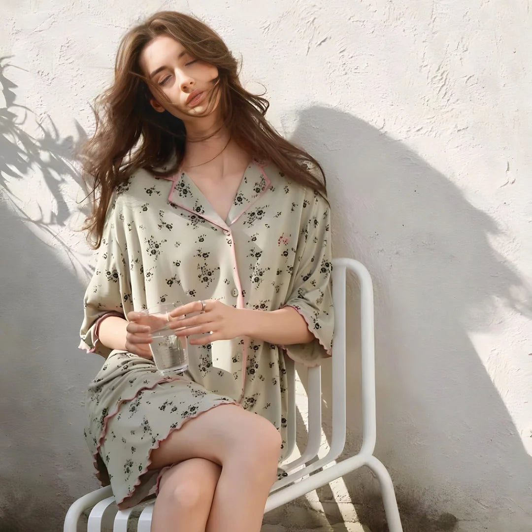 Model relaxing on a white chair in the sun, wearing the comfortable sage green floral pajama set. - RoomDen