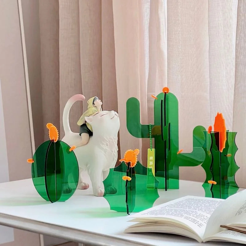 Four styles of the acrylic cactus decor set arranged on a white desk with a cat figurine and an open book - RoomDen